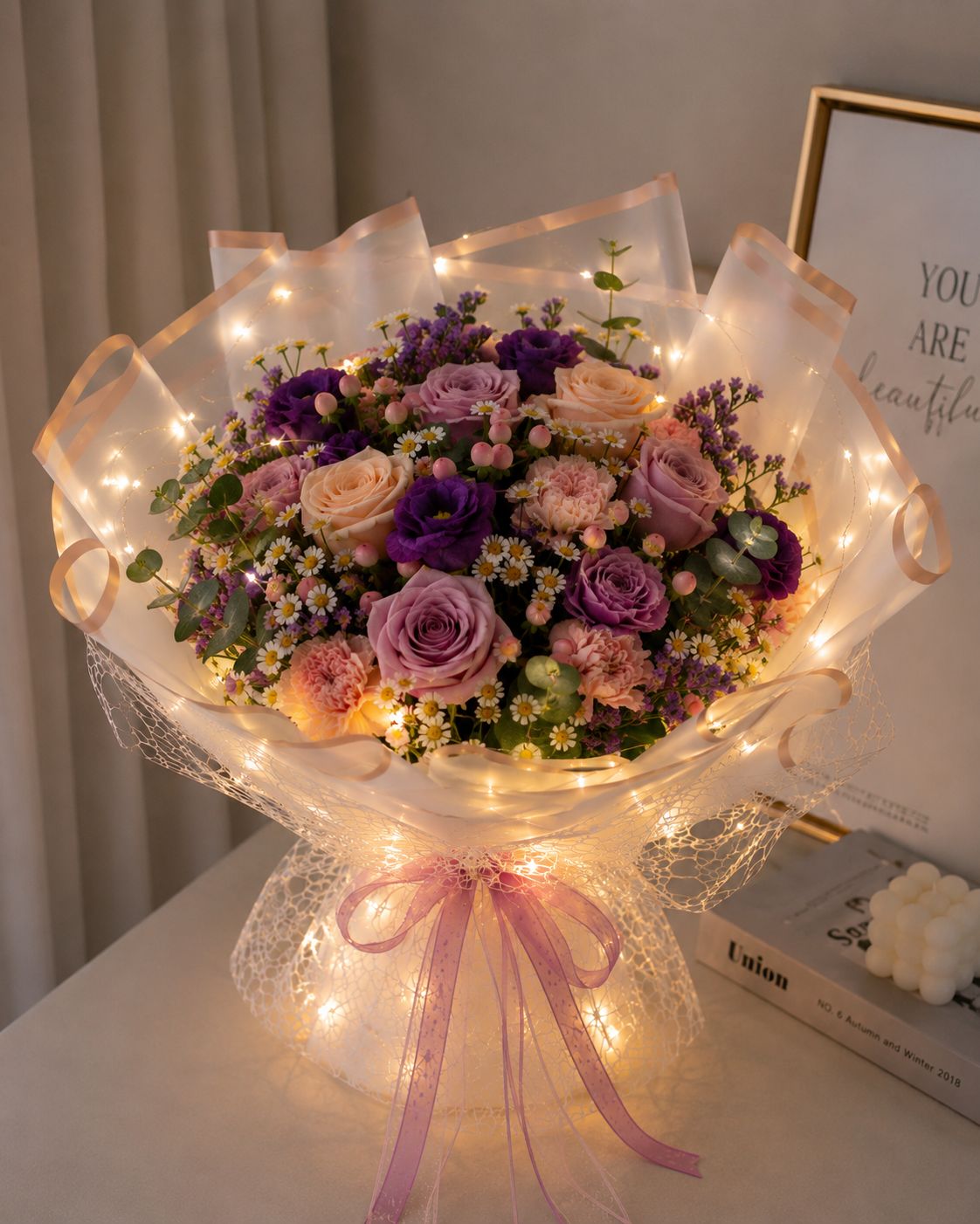 A bright arrangement with darker roses and dark lisianthus with a glowing ribbon